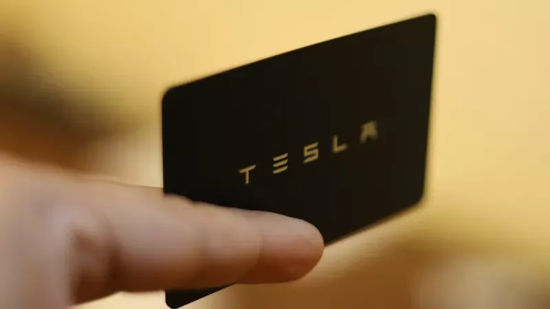 A close up of a man handing a black Tesla business card to a client.