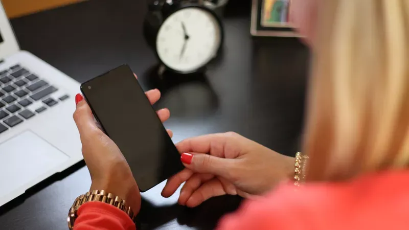 Woman with a phone at a desk.