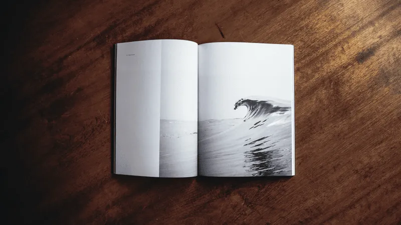 Book on a wood table opened to a page with an ocean wave.